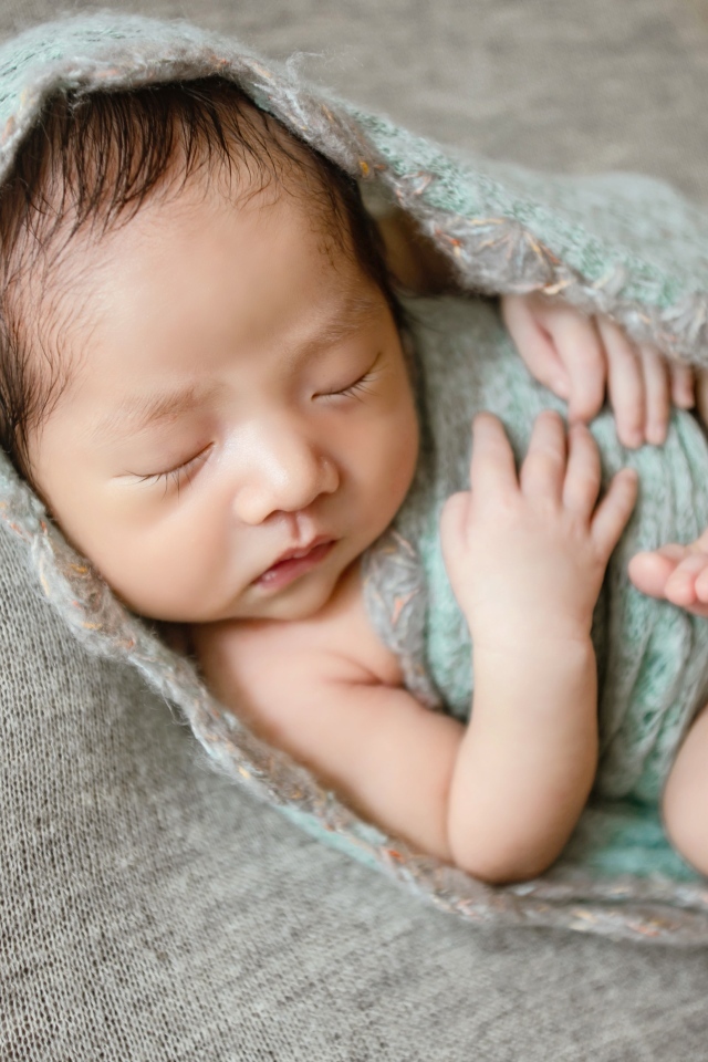 Крошечный новорожденный малыш на сером фоне