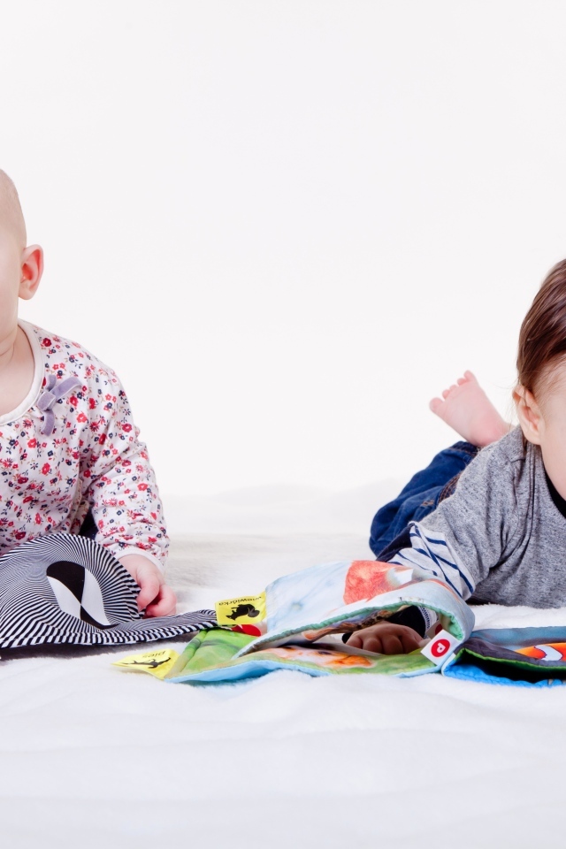 Два маленьких ребенка на кровати с мягкими книгами