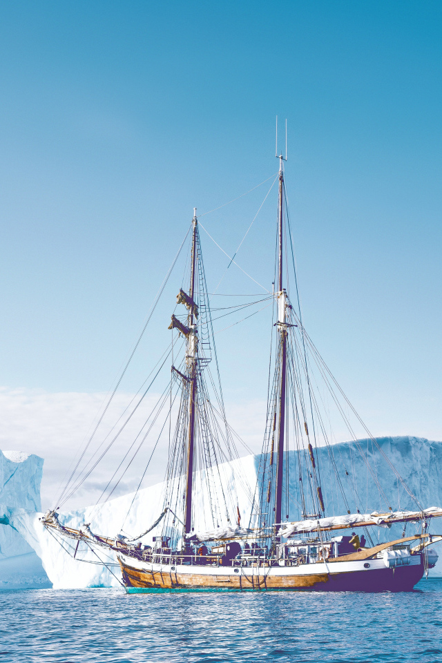 Большой корабль подплывает к голубому айсбергу в море