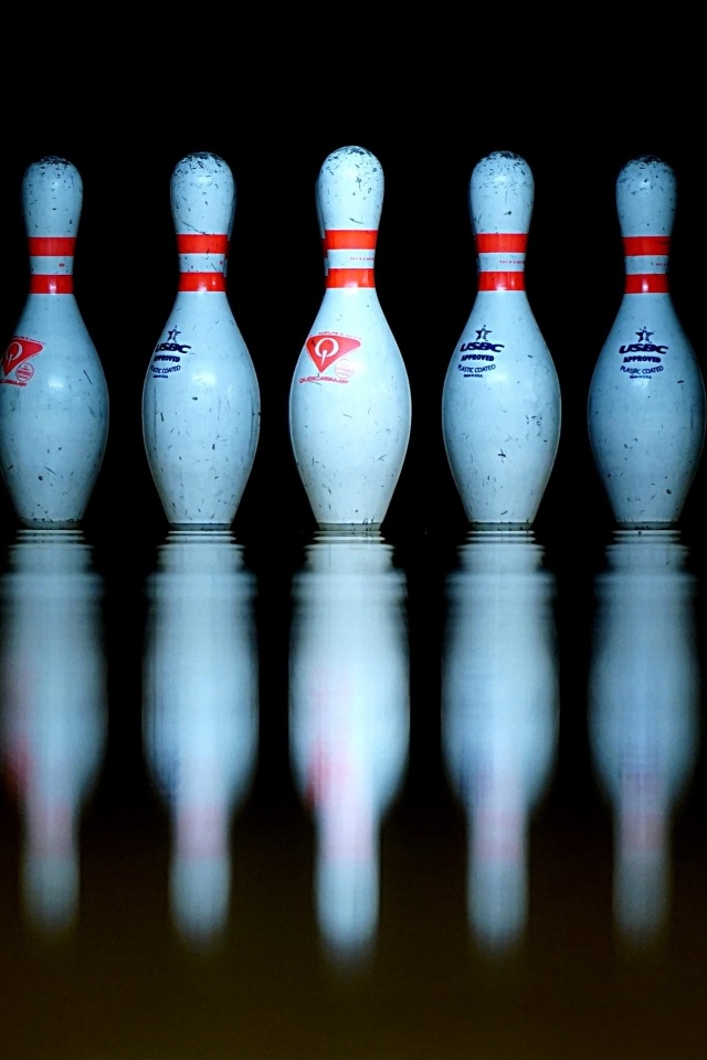 Кегли для боулинга отражаются в черной поверхности 