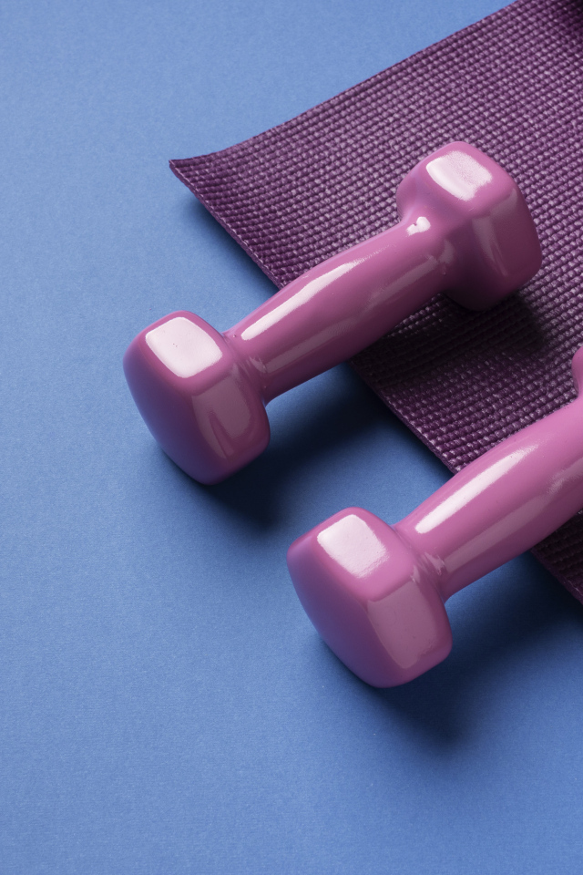 Розовые гантели и коврик на голубом фоне