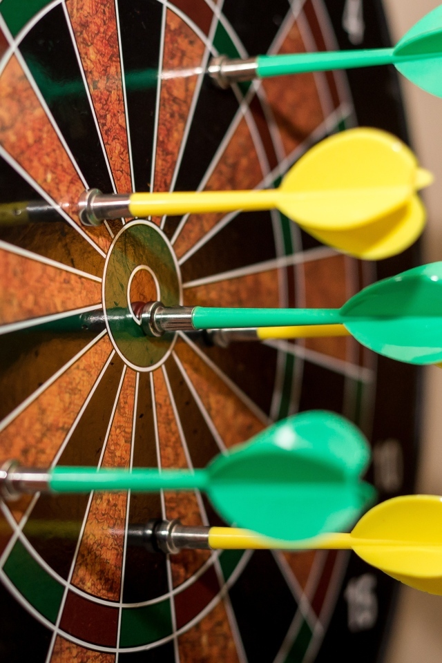 Желтые и зеленые дротики в мишени 