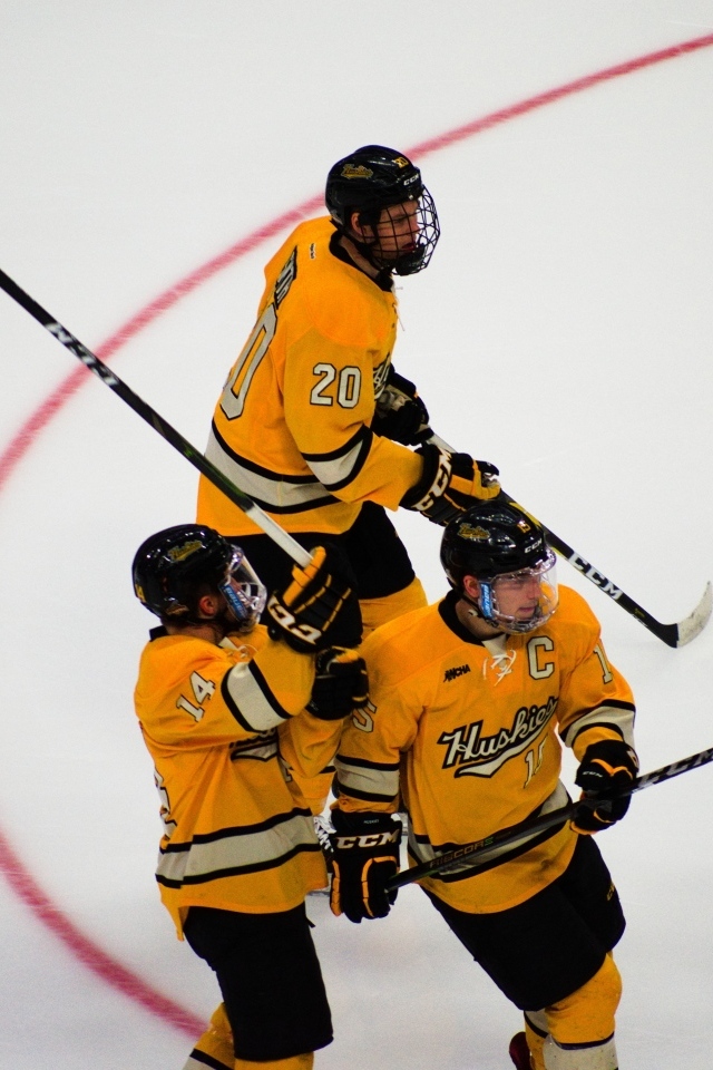 Три хоккеиста с клюшками на льду