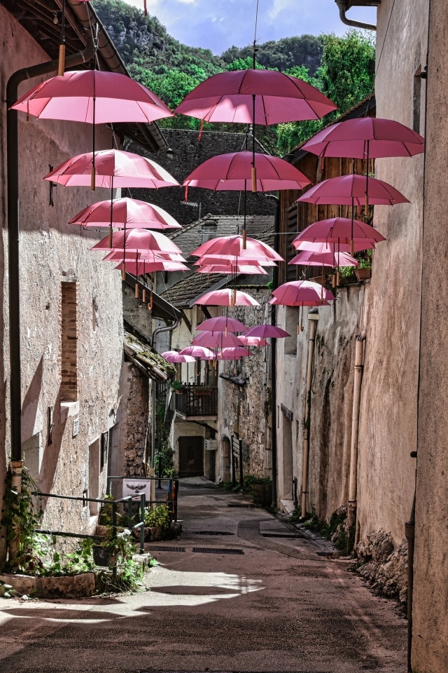 Розовые зонтики украшают узкую улицу