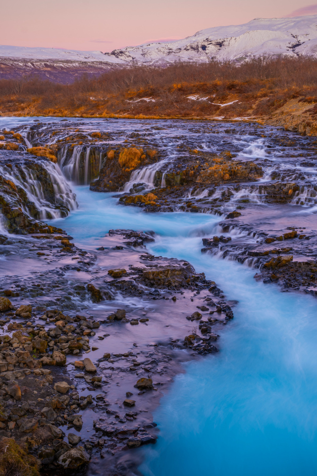 Быстрая река стекает по камням в горах Исландии