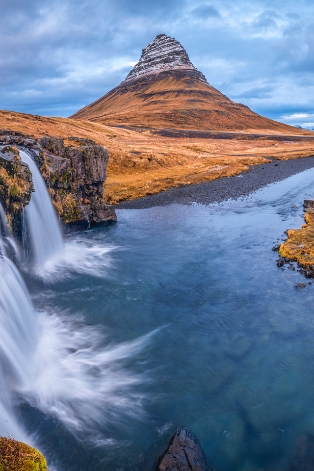 Вид на реку, водопад и гору Киркьюфетль под пасмурным небом Исладнии