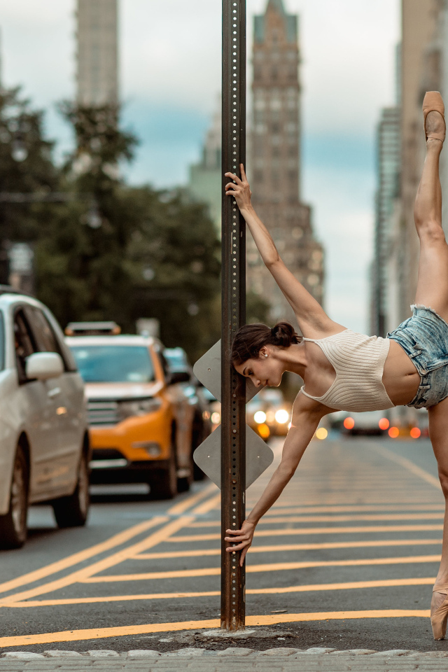 Девушка делает шпагат у столба в городе