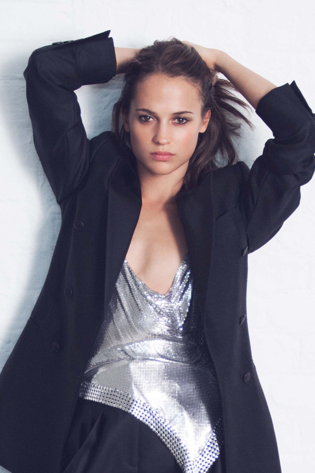 Актриса Алисия Викандер в черном костюме стоит у стены