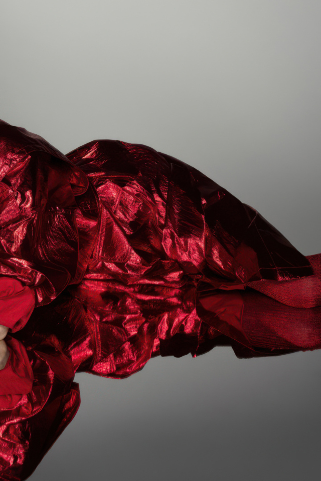 Актриса Анна Кендрик в красном костюме на сером фоне