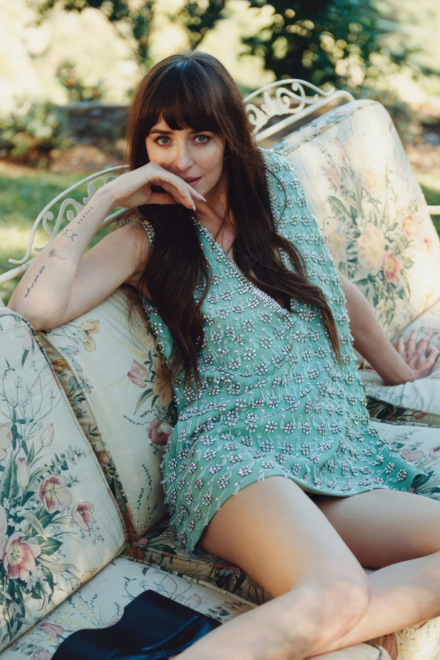 Актриса Дакота Джонсон в платье сидит на диване