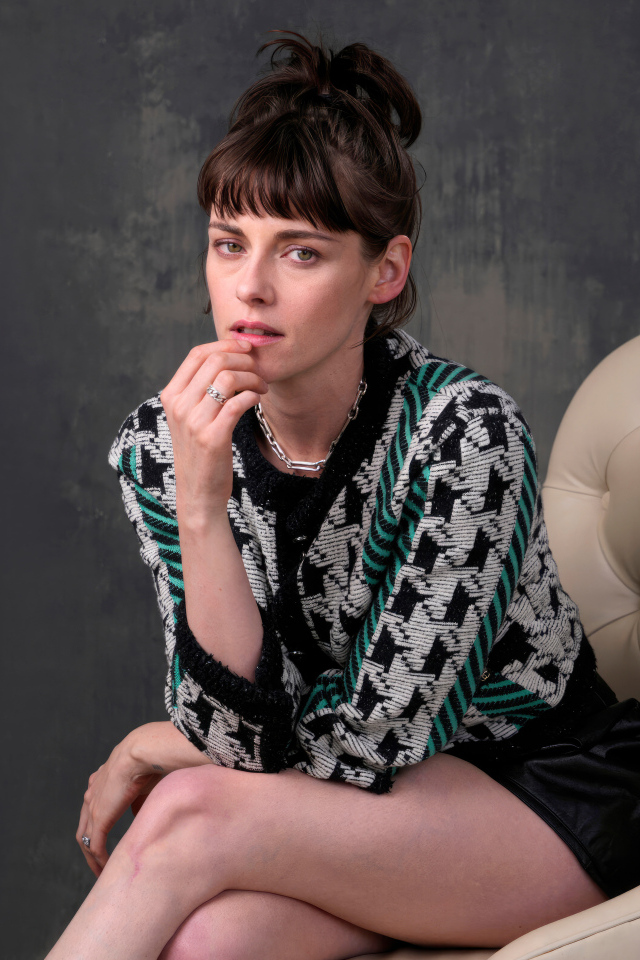 Актриса Кристен Стюарт сидит в кресле на фоне серой стены