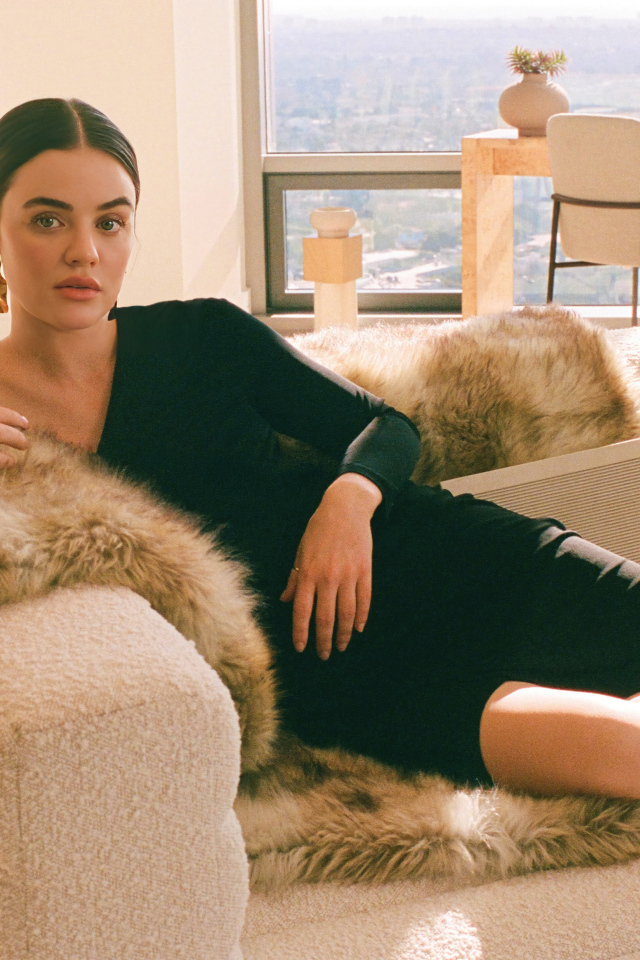 Актриса Люси Хейл в черном платье лежит на диване