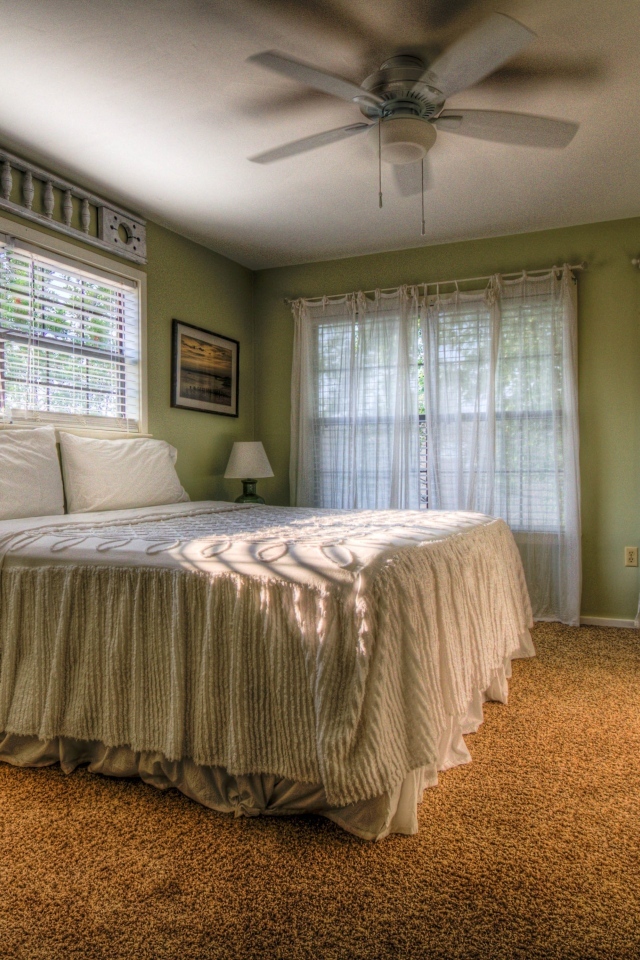 Спальня в зеленых тонах с высокой кроватью 