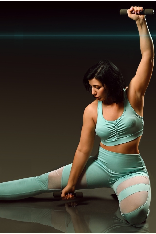 Девушка занимается фитнесом с гантелями