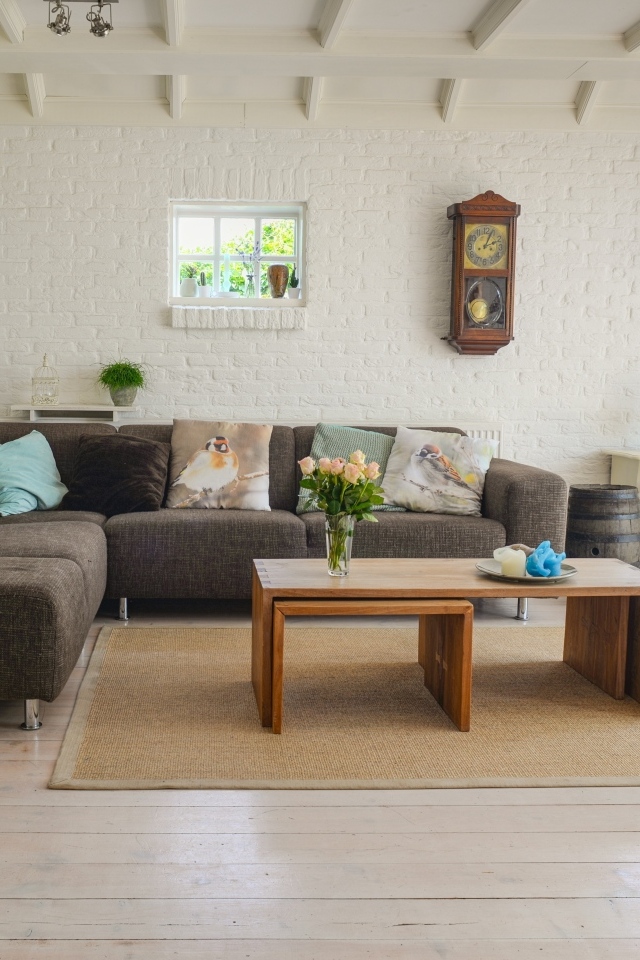 Большая комната с серым диваном и белыми стенами