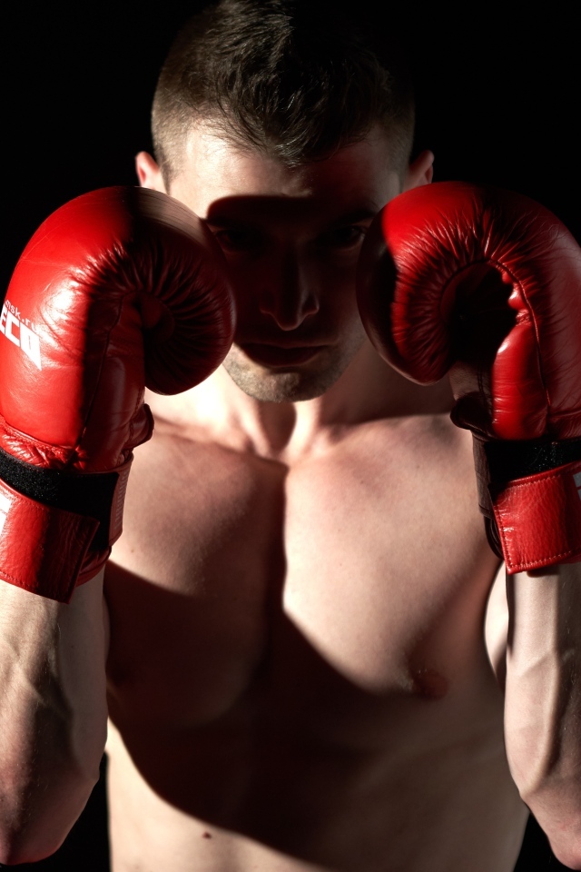 Мужчина в стойке в красных боксерских перчатках 