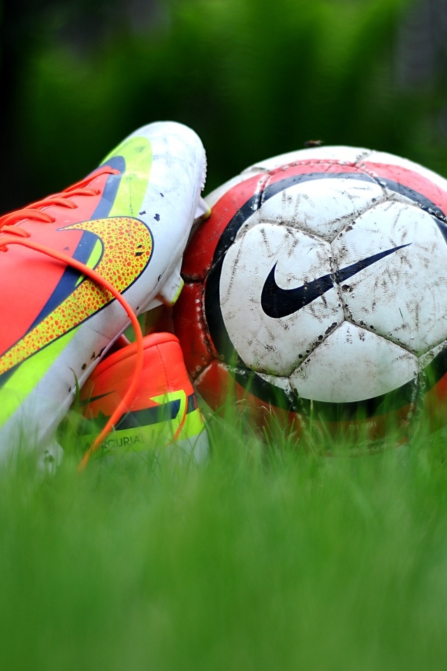 Футбольный мяч и бутсу на зеленой траве