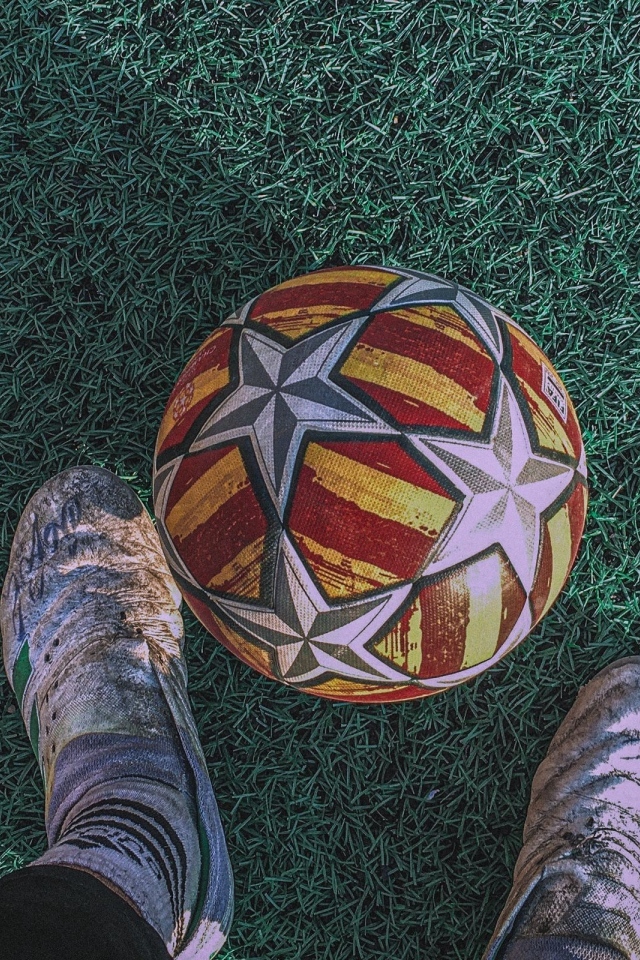 Футбольный мяч на зеленом поле с ногами футболиста