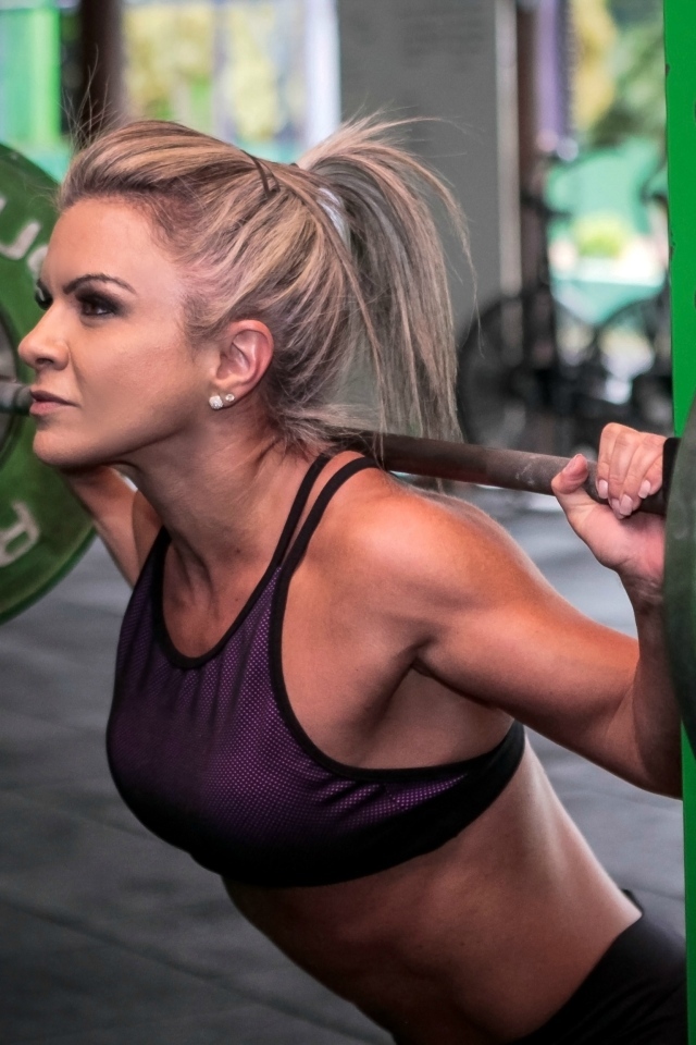 Сильная спортивная девушка поднимает штангу