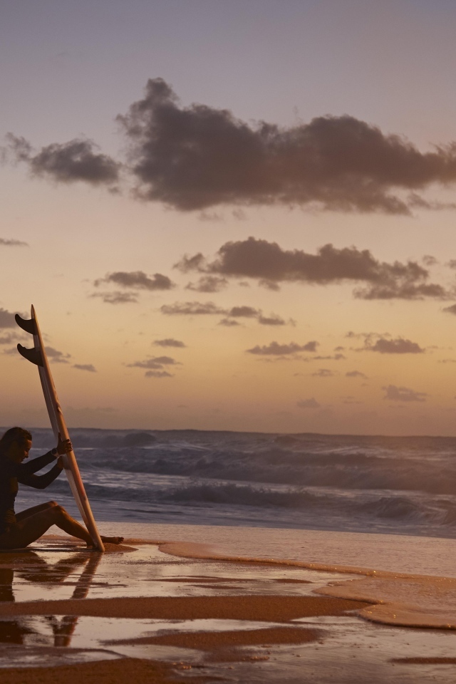 Девушка серфингистка сидит на берегу моря