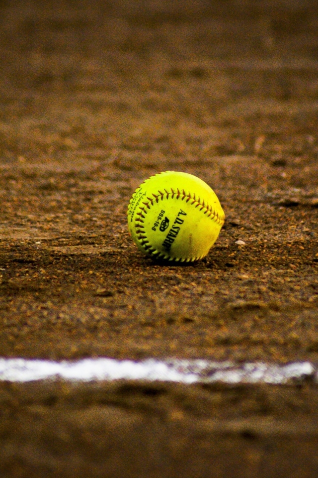 Желтый бейсбольный мяч на песке