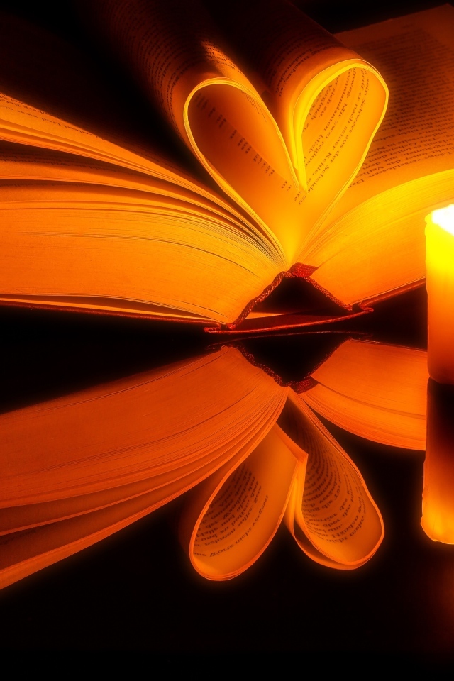 Открытая книга с зажженной свечой отражаются в черной поверхности