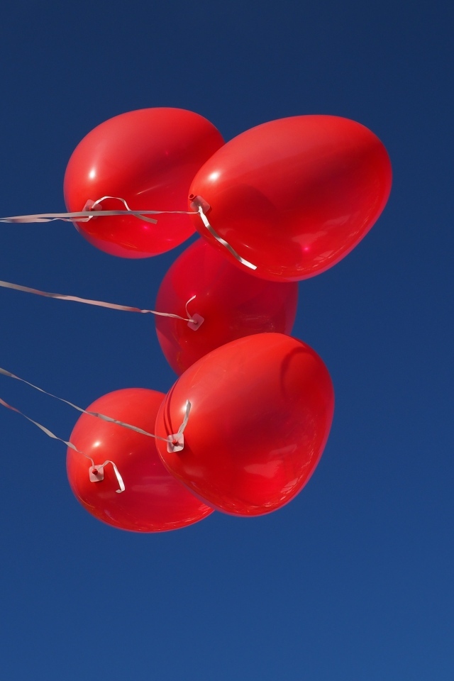 Красные воздушные шары на нитке на фоне голубого неба