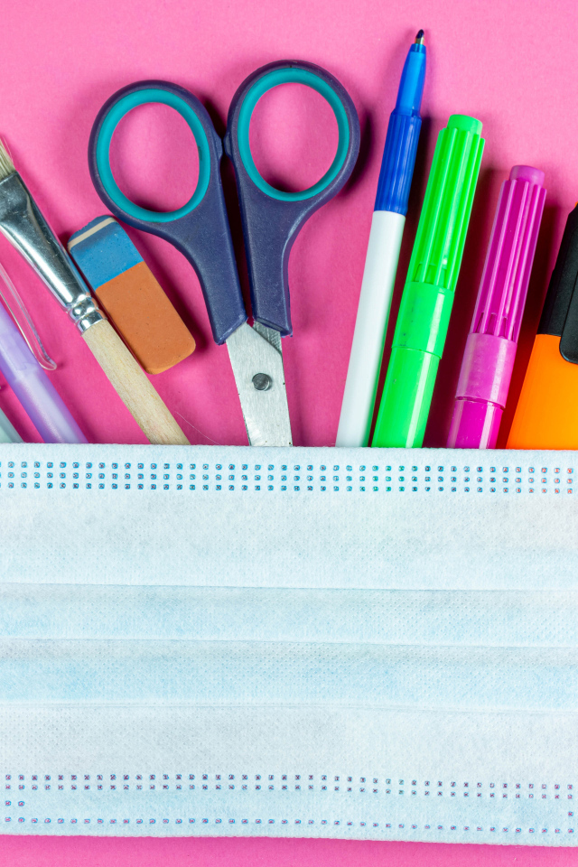 Канцелярские предметы и медицинская маска на розовом фоне