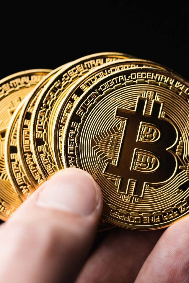 Монеты биткоин в руке на черном фоне