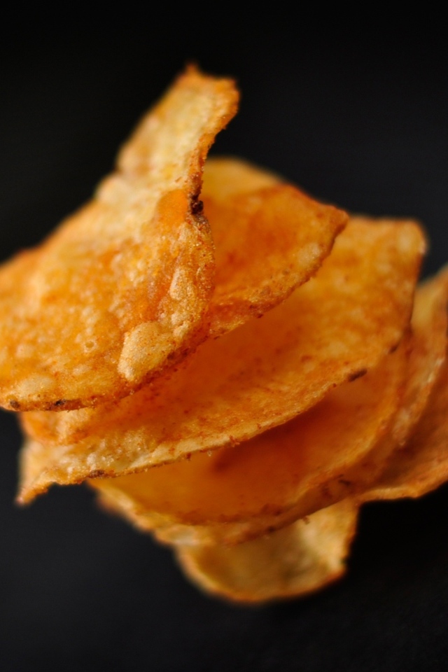 Хрустящие картофельные чипсы на черном фоне