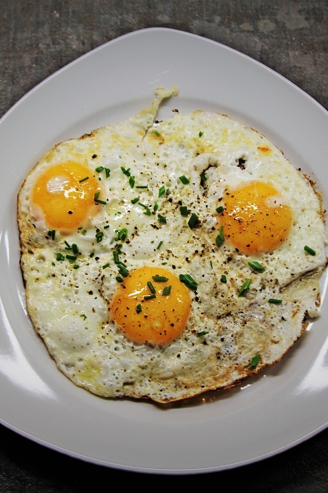 Яичница глазунья в тарелке на сером столе