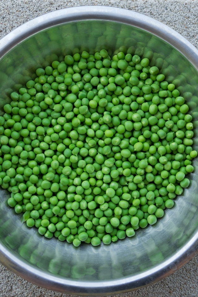 Зеленый горошек в жестяной миске на столе
