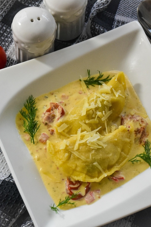 Равиоли с соусе с беконом на тарелке