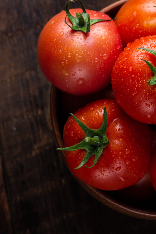 Мокрые красные томаты с миске на столе