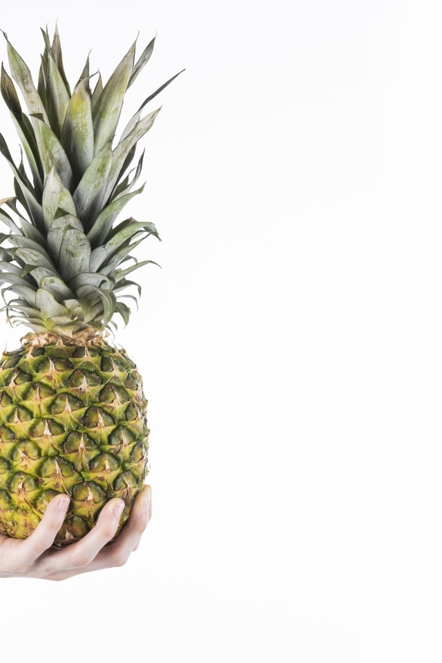 Большой ананас в руке на белом фоне