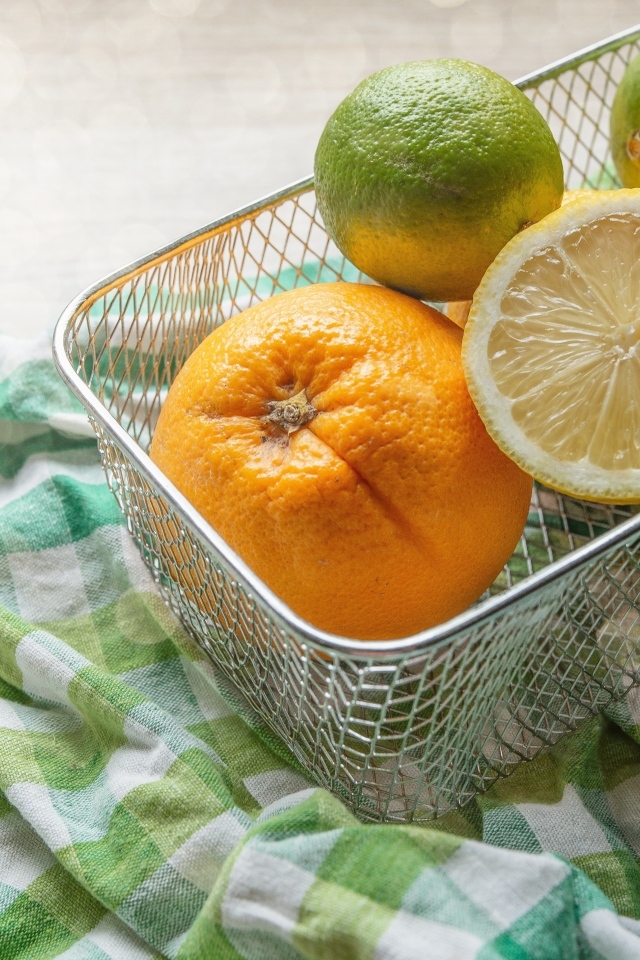 Цитрусовые фрукты в железной корзине на столе