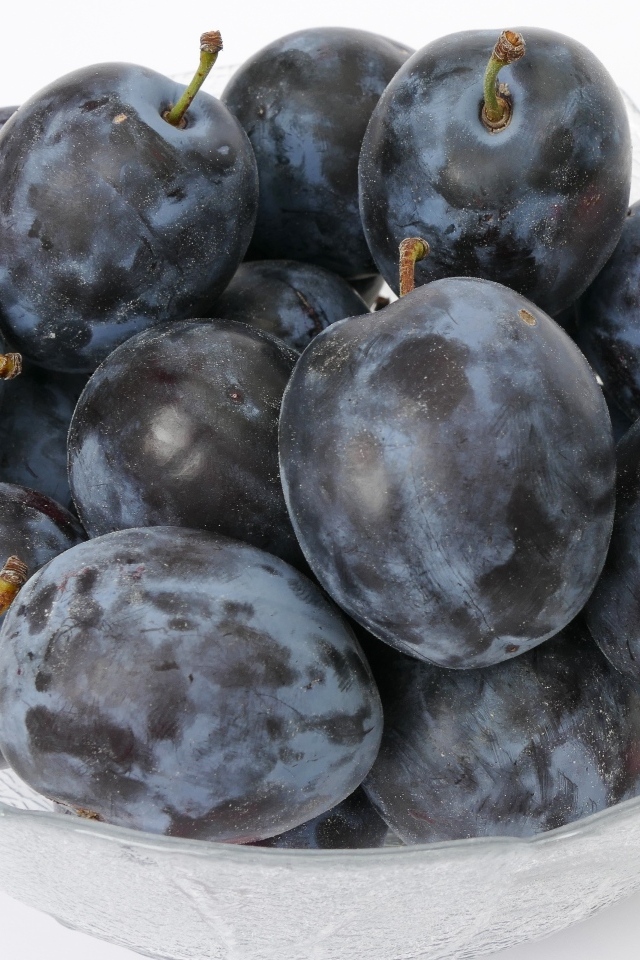 Стеклянная тарелка с вкусными синими сливами