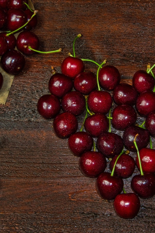 Сердце из спелых ягод черешни на деревянном столе