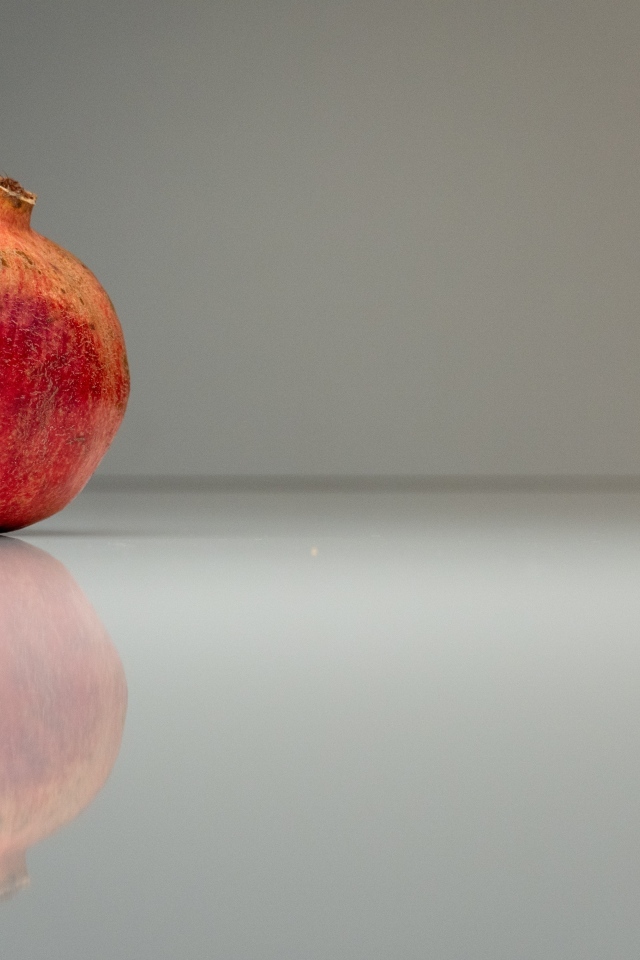 Красный гранат отражается в поверхности на сером фоне