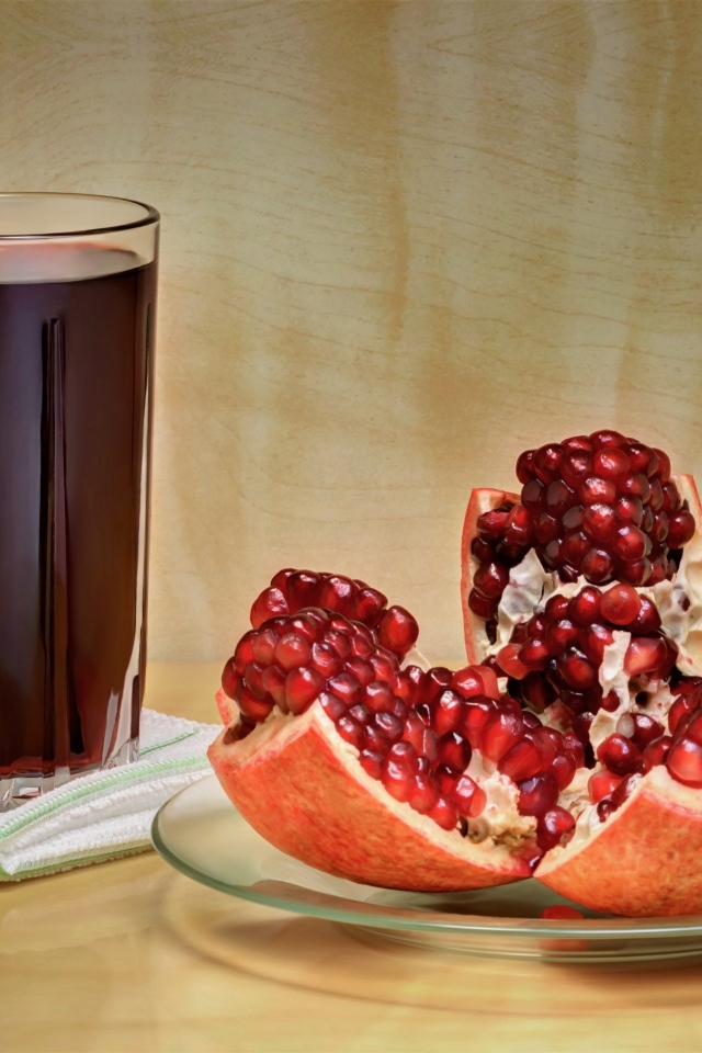 Красный гранат на столе со стаканом сока