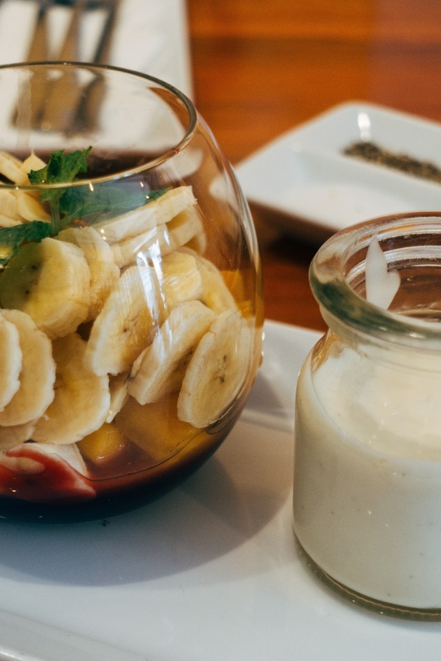 Нарезанные бананы в стакане на столе с йогуртом