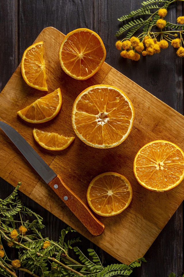 Нарезанный апельсин на доске на столе с цветами