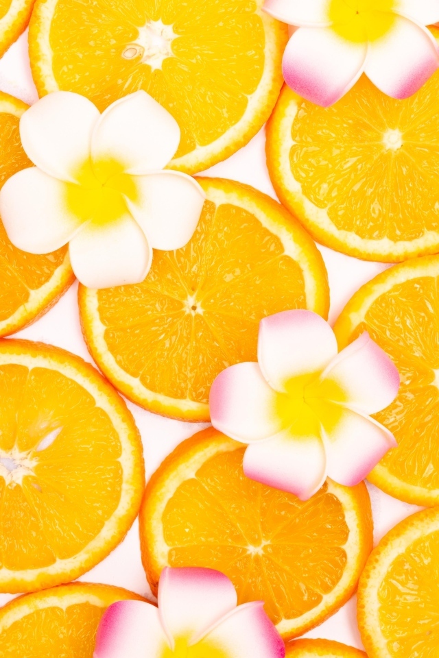 Нарезанный апельсин с цветами плюмерии для фона