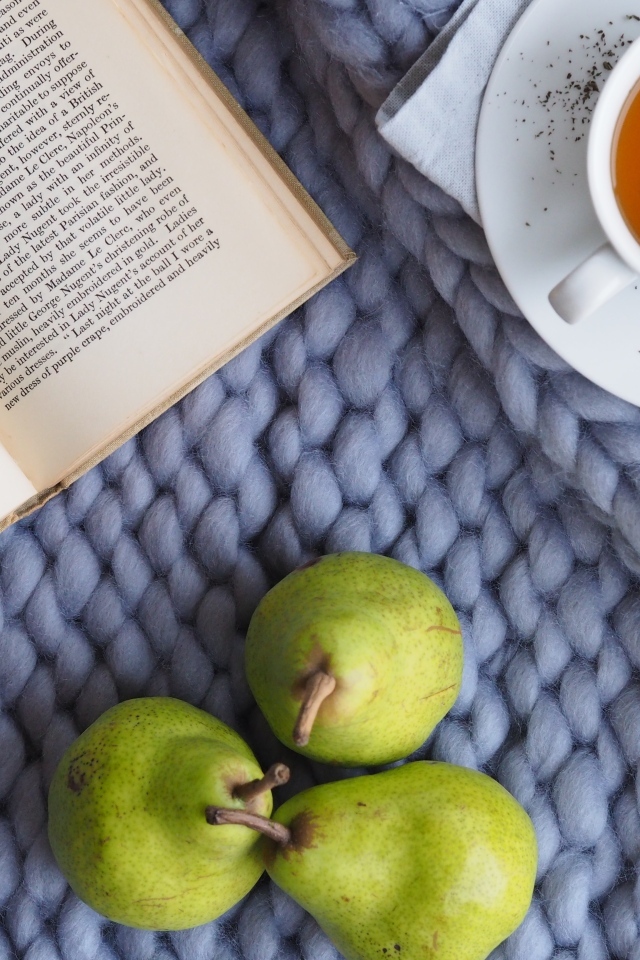 Три зеленые груши на столе с чаем и книгой