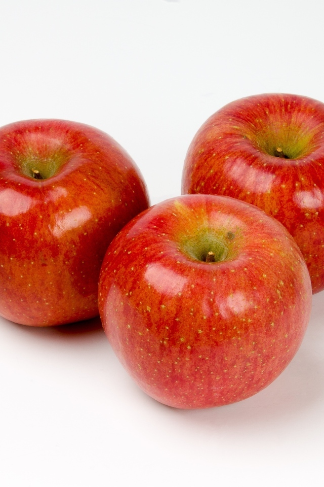 Три красных яблока на белом фоне