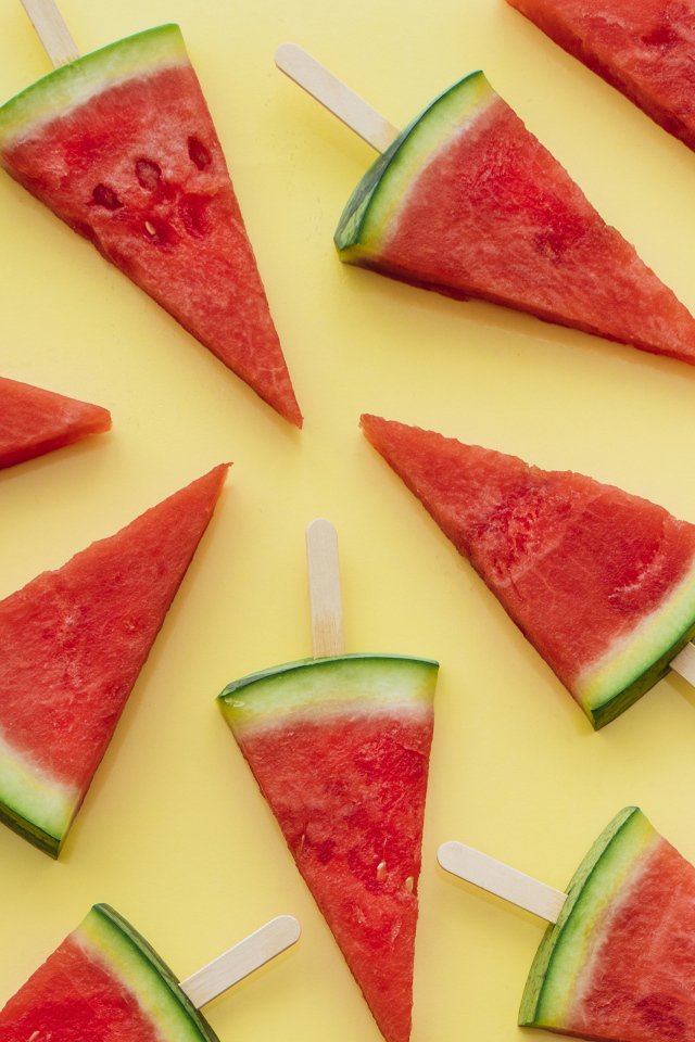Куски арбуза на палочке на желтом фоне