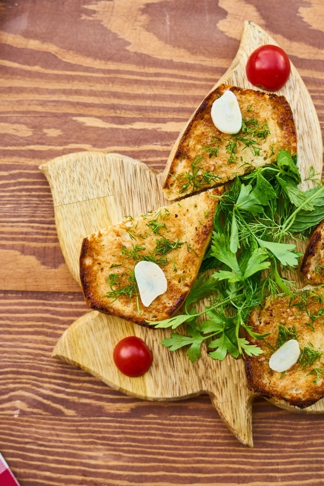Гренки с чесноком и зеленью на разделочной доске на столе
