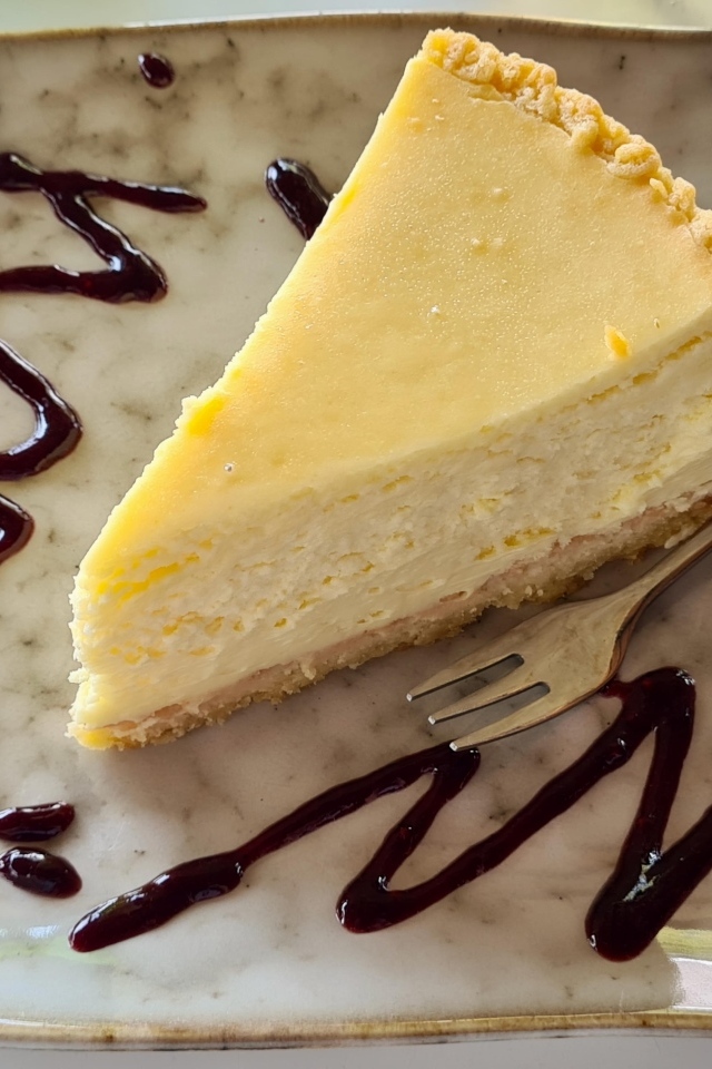 Кусок чизкейка с шоколадным топпингом на тарелке