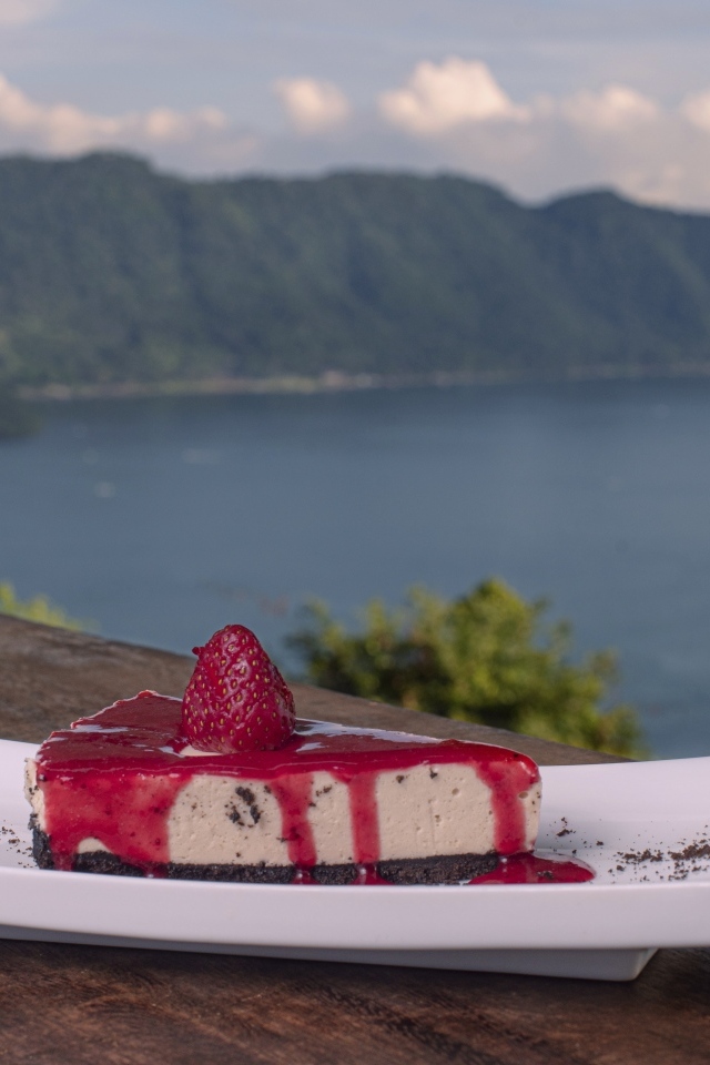 Кусок чизкейка с клубничным джемом на фоне моря