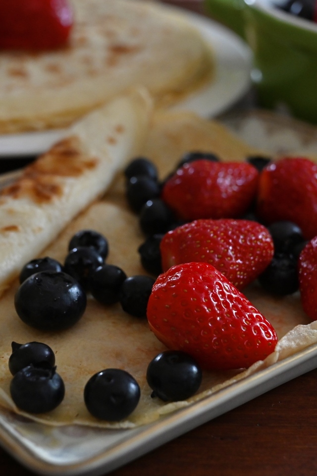 Блин с ягодами черники и клубники на тарелке